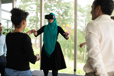 Businesswoman holding hand of colleague wearing virtual reality simulator during kick off meeting at convention center