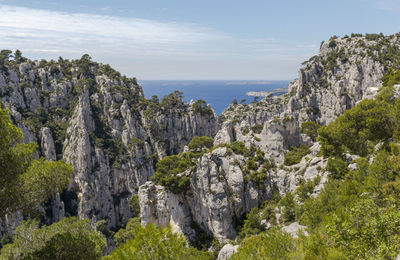 Scenic view of rocky mountains by sea against sky