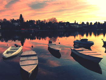 Boats moored in lake against sky during sunset