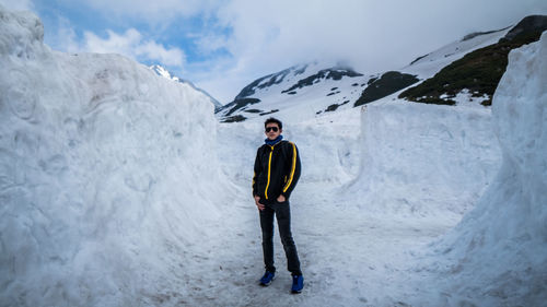 Full length of young man standing amidst snow covered rocks