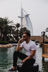 Young man sitting against water