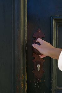 Female hand opening dark green old wooden door