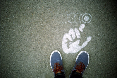 Low section of man standing by hand painted on street