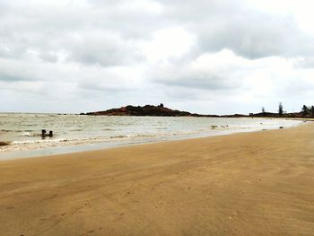 Scenic view of beach against cloudy sky
