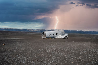 Lightning over broken airplane wreck at black sand beach in solheimasandur