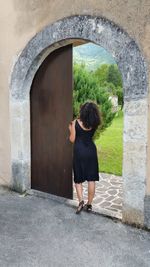 Rear view full length of woman standing by arch door
