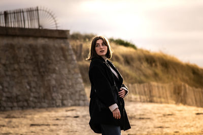 Portrait of young woman standing against sky