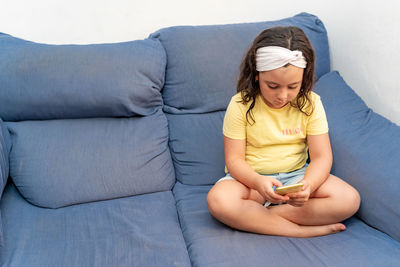 Full length of woman sitting on sofa at home