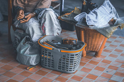 Low section of woman sitting on wicker basket