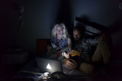 Young woman using mobile phone while sitting on bed