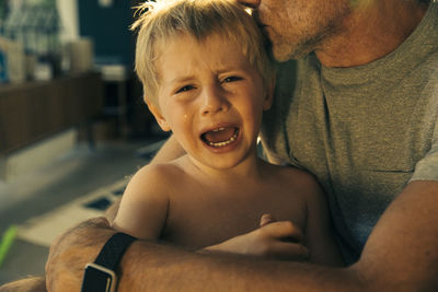 Portrait of shirtless boy with baby at home