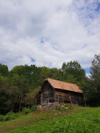 House and trees on field against sky