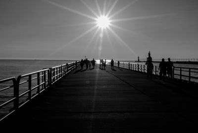 People on promenade by sea against sky