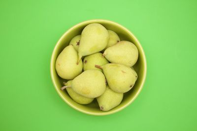 Directly above shot of fruits in bowl over green background