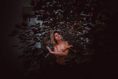 Shirtless woman standing against trees