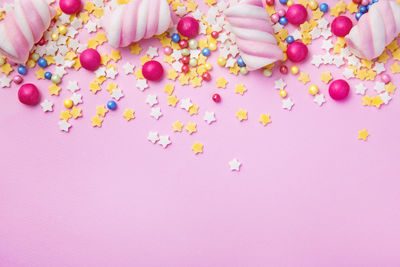 Directly above shot of marshmallows and candies on pink background