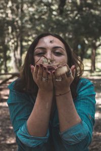 Portrait of beautiful young woman blowing leaves