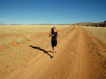 Full length of woman running on country road