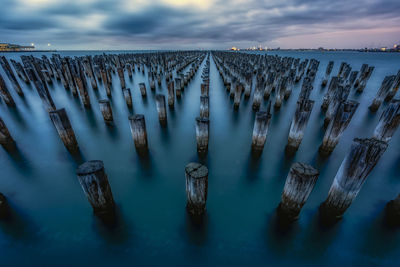 Panoramic view of wooden posts in sea against sky