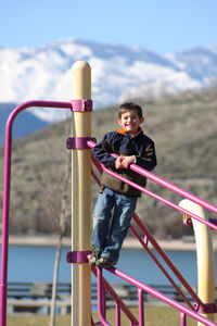 Portrait of boy standing on outdoor play equipment at playground