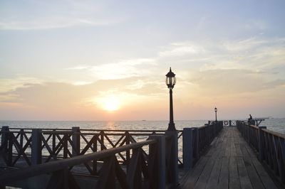 Pier on sea against sky during sunset