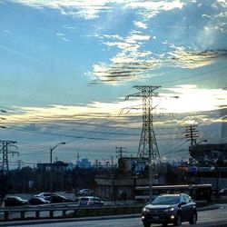 Cars on road against cloudy sky