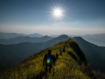 Rear view of people walking on ridge against sky