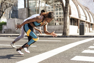 Young man and woman practicing for sports race while running in city