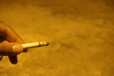 Cropped hand holding cigarette at night