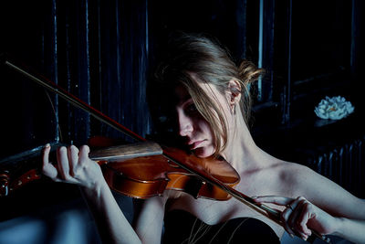 Young woman playing violin in uber aesthetic environment 