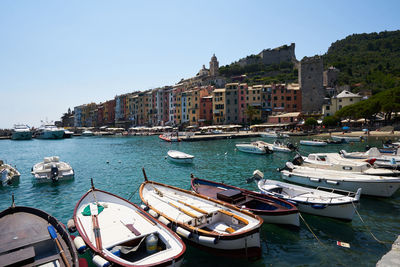 Boats moored in harbor by buildings against clear sky