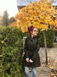 Full length of young woman standing by flower tree