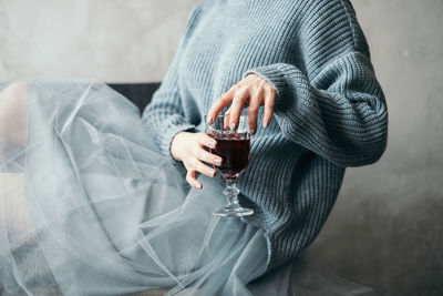 Midsection of woman having red wine at home