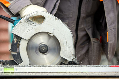 Midsection of man using circular saw in workshop