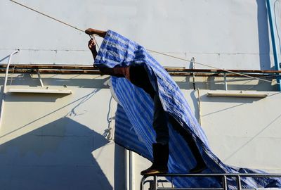 Man applying tarpaulin on rope