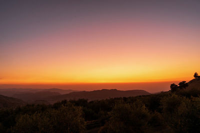 Scenic view of silhouette landscape against orange sky