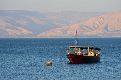 Fishing boat in sea against mountains