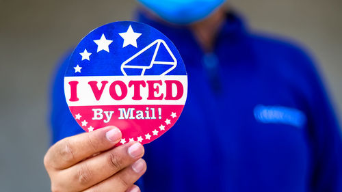 Close-up of hand holding text against blue background