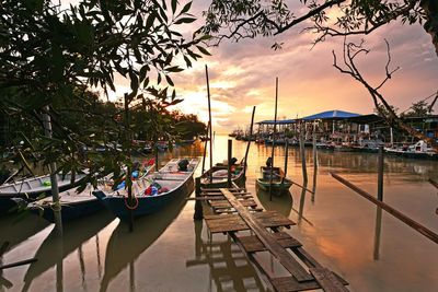 Fishing boats moored on sea at sunset