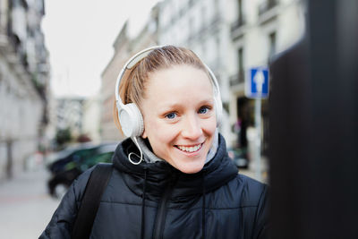 Portrait of smiling young woman listening outdoors