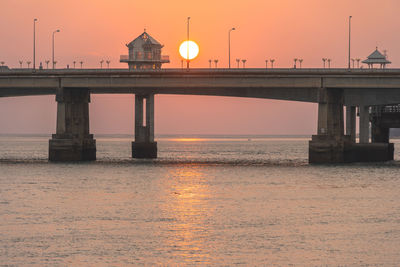 Bridge over sea against sky during sunset