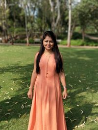 Portrait of smiling young woman standing on grass