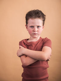 Portrait of boy standing against gray background