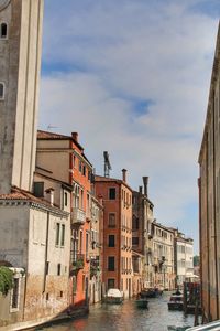 Canal amidst buildings in city against sky