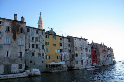 Boats on sea by buildings against clear sky