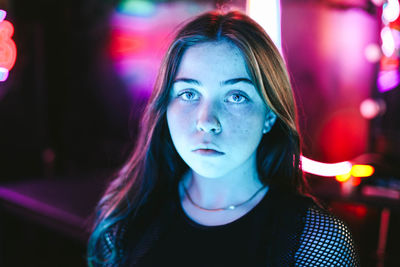 Portrait of beautiful young woman against illuminated lights