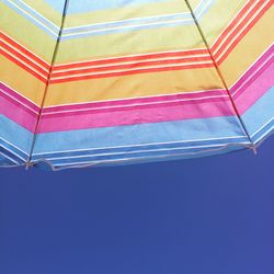 Low angle view of parasol against clear blue sky