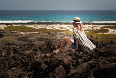 Woman sitting on beach against clear sky