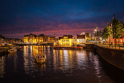 Bridge over river by buildings against sky at night