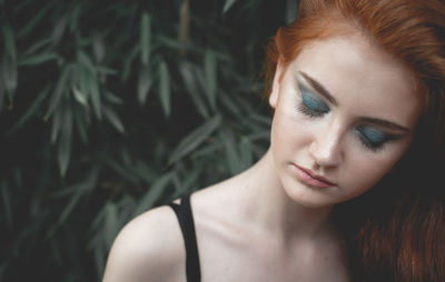 Close-up of young woman with make-up against plants